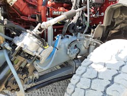 Electric motor, in the silver-colored casing atop the steering gearbox, adds up to 10.7 foot-pounds of effort as ordered by sensors and electronic controls. This steadies the column and steering wheel over rough terrain off-road, and in crosswinds and on crowned highway surfaces, Mack says.