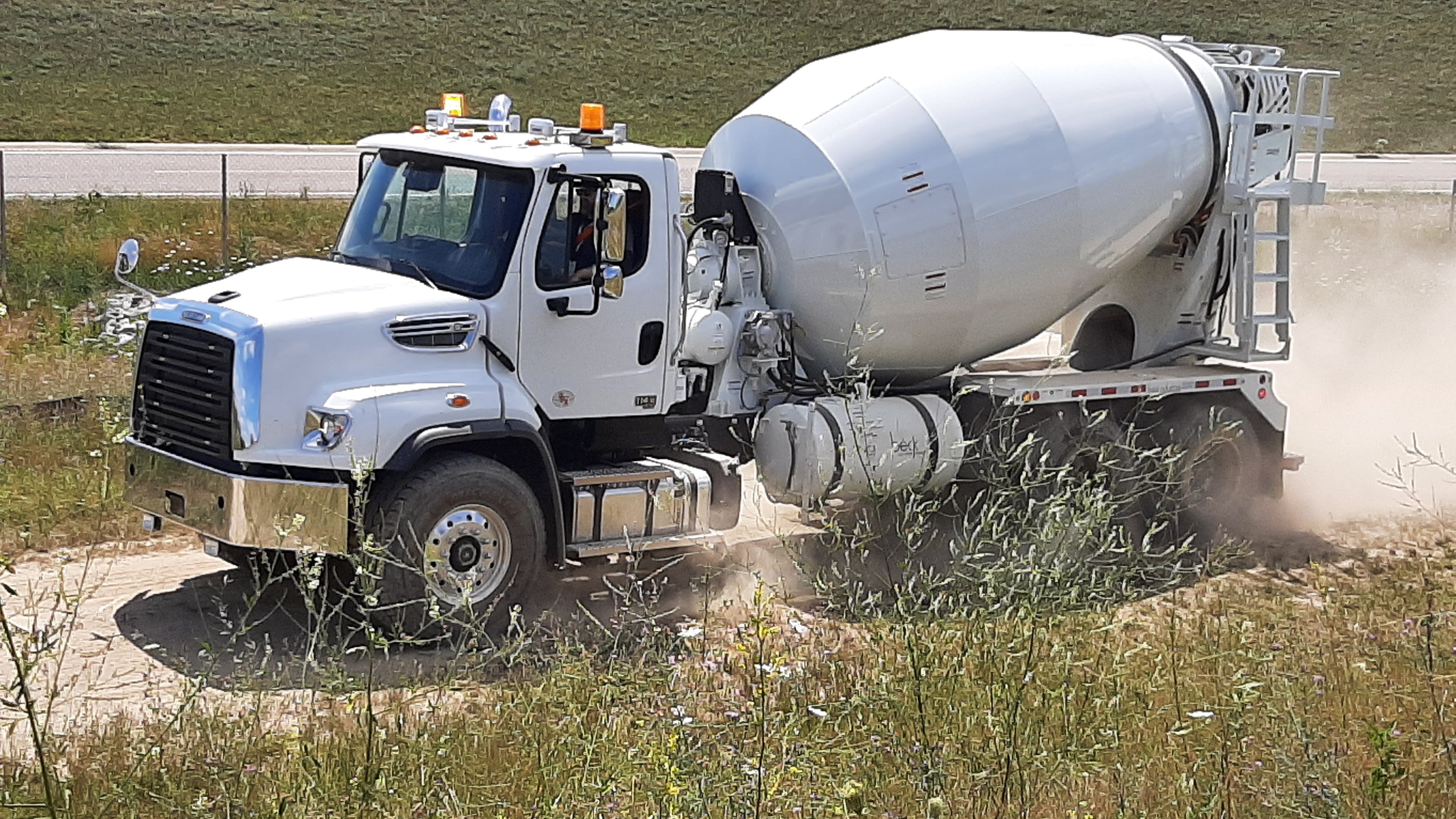 The 114SD Plus mixer truck scoots along a gravel trail at a test center outside Ypsilanti. Rough portions of two off-road courses gave the chassis a workout, but it never faltered. Not used here were the Detroit Assurance safety systems that can help prevent accidents on highways. Powertrain includes a 440-horsepower Cummins X12, an Allison automatic, and Meritor rear axles.