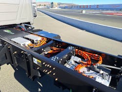 MD-E’s Sea Electric powertrain components nestle between the frame rails behind the cab. From left are a battery pack, a pair of controllers, and the electric motor, all linked by orange-colored 400-v cables. MD-E’s Sea Electric powertrain components nestle between the frame rails behind the cab. From left are a battery pack, a pair of controllers, and the electric motor, all linked by orange-colored 400-v cables.