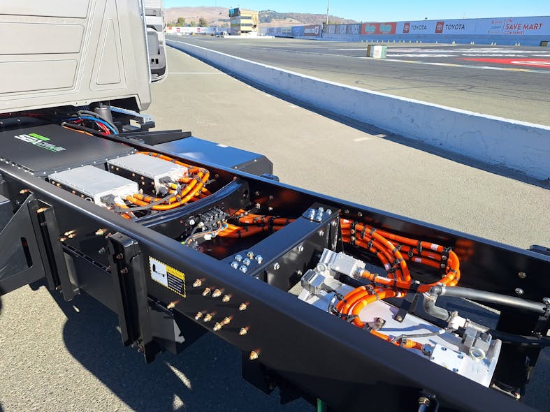MD-E&rsquo;s Sea Electric powertrain components nestle between the frame rails behind the cab. From left are a battery pack, a pair of controllers, and the electric motor, all linked by orange-colored 400-v cables.