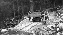 Braking a loaded flatbed dump cart downhill by hand, although difficult, beats wheelbarrows. Temporary railroads were widely used in material handling before the advent of trucks and were phased out entirely except in special circumstances by the 1930s. Even more anachronistically, the cart was also loaded by hand.