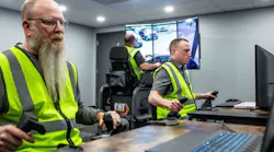Three operator trainees work together in Cat Simulators Collaborative Worksite Training, cleaning up a spoil pile with a dozer and loading the material into an articulated truck with an excavator.