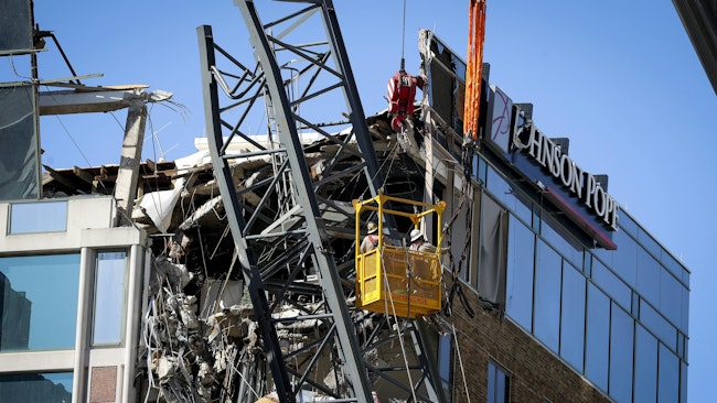 Workers are suspended in a basket near part of a fallen crane that sits atop the building at 490 First Ave. S. on Oct. 23, 2024 in St. Petersburg. The crane broke off and landed on the building during the high winds of Hurricane Milton.