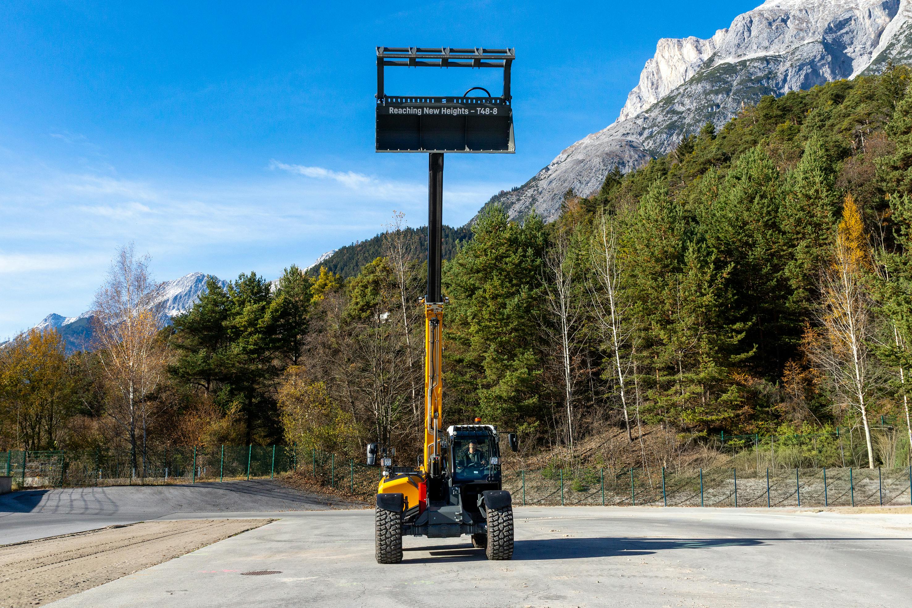 Liebherr T48-8s Telehandler with grapple bucket attachment reaching high into the sky