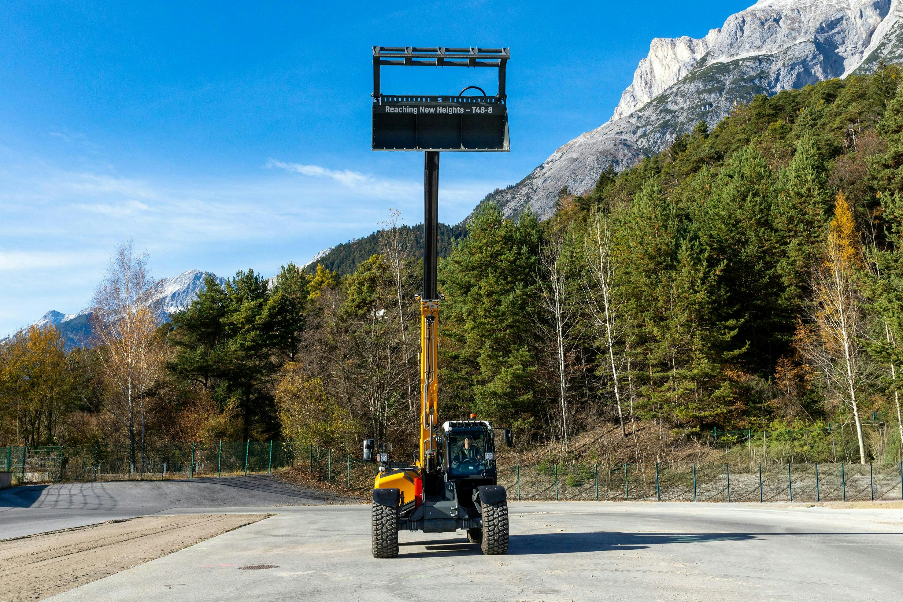Liebherr T48-8s Telehandler with grapple bucket attachment reaching high into the sky