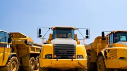 Heavy duty construction trucks. A view of the front of yellow, heavy duty earthmoving trucks on a construction site.
