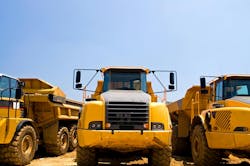 Heavy duty construction trucks. A view of the front of yellow, heavy duty earthmoving trucks on a construction site. Heavy duty construction trucks. A view of the front of yellow, heavy duty earthmoving trucks on a construction site.