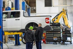 Fleetio shop image with guys looking at a truck and a cat backhoe in the background Fleetio shop image with guys looking at a truck and a cat backhoe in the background