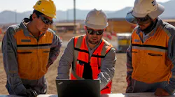 Contractors with Cat helmets look at a laptop.