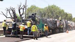 Vögele Products paver paving a road with men in the daytime. Vögele Products paver paving a road with men in the daytime.