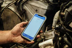 Fleetio software on a phone over and engine compartment Fleetio software on a phone over and engine compartment