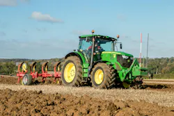 Modern John Deere tractor pulling a plough. Green modern John Deere tractor and plough competing at a English ploughing match Modern John Deere tractor pulling a plough. Green modern John Deere tractor and plough competing at a English ploughing match