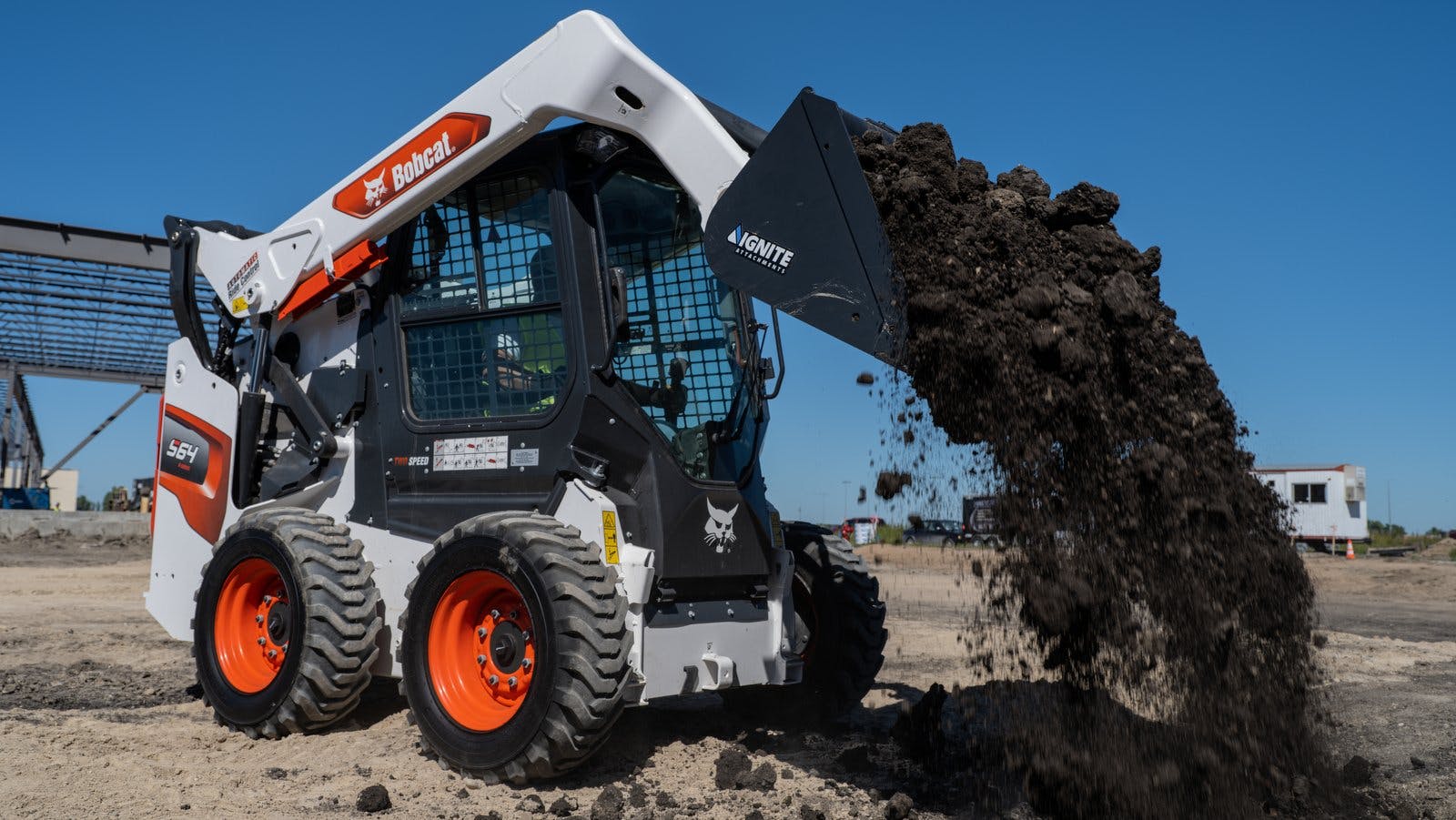 Ignite bucket on a Bobcat skid steer, dumping dirt.