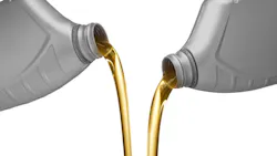 Engine oil being poured from containers on a white background. Engine oil being poured from containers on a white background.