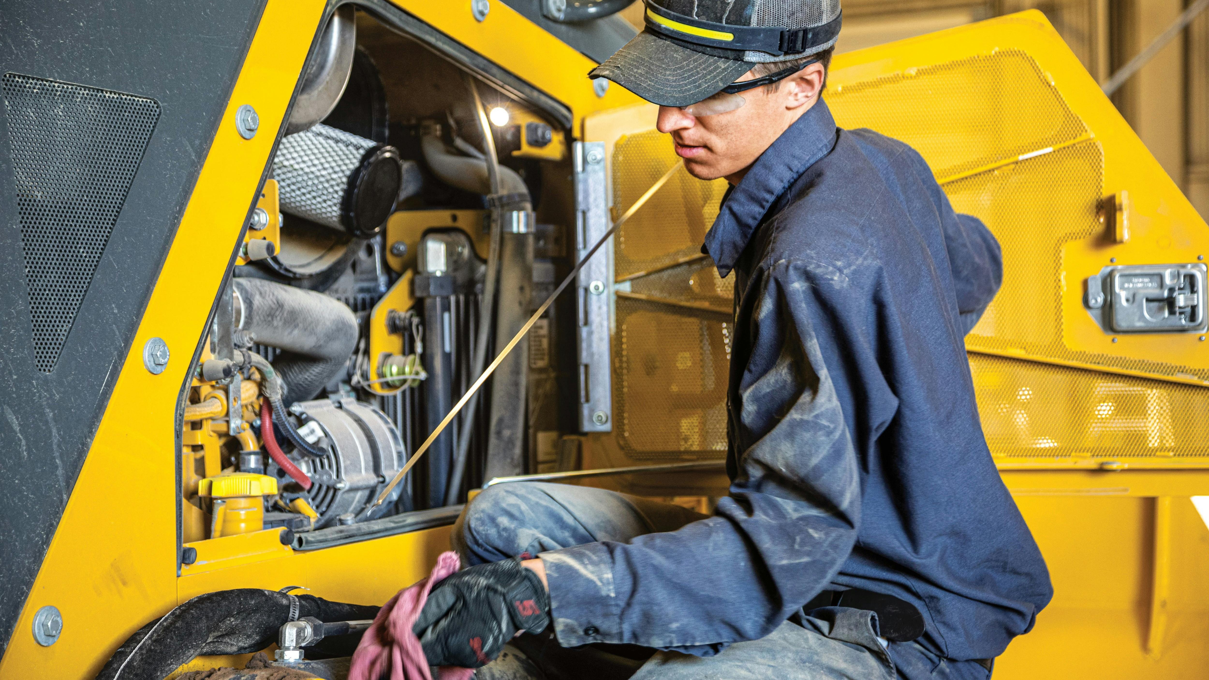 Mechanic checking the oil on a John Deere machine.