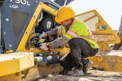 John Deere oil change, worker pours oil into a machine. John Deere oil change, worker pours oil into a machine.