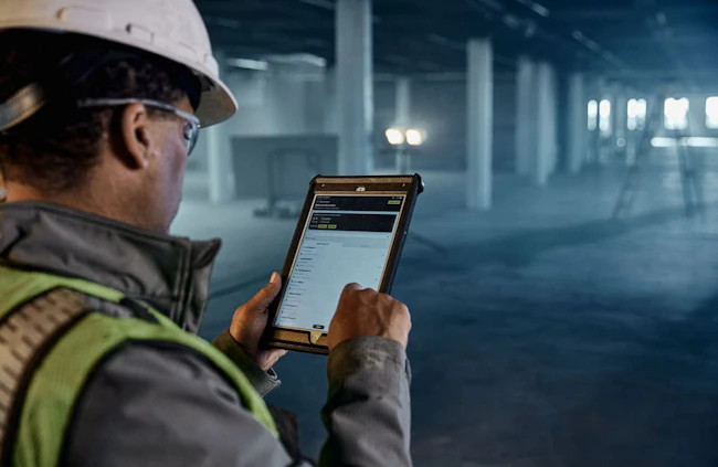 Dewalt Ecomm Tool connect image. Man on tablet inside building.