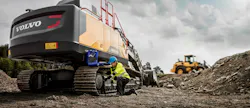Volvo Construction Equipment excavator. Man greasing undercarriage. Volvo Construction Equipment excavator. Man greasing undercarriage.