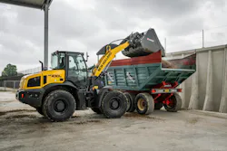 New Holland Construction W100D wheel loader dumping dirt into a dump truck. New Holland Construction W100D wheel loader dumping dirt into a dump truck.
