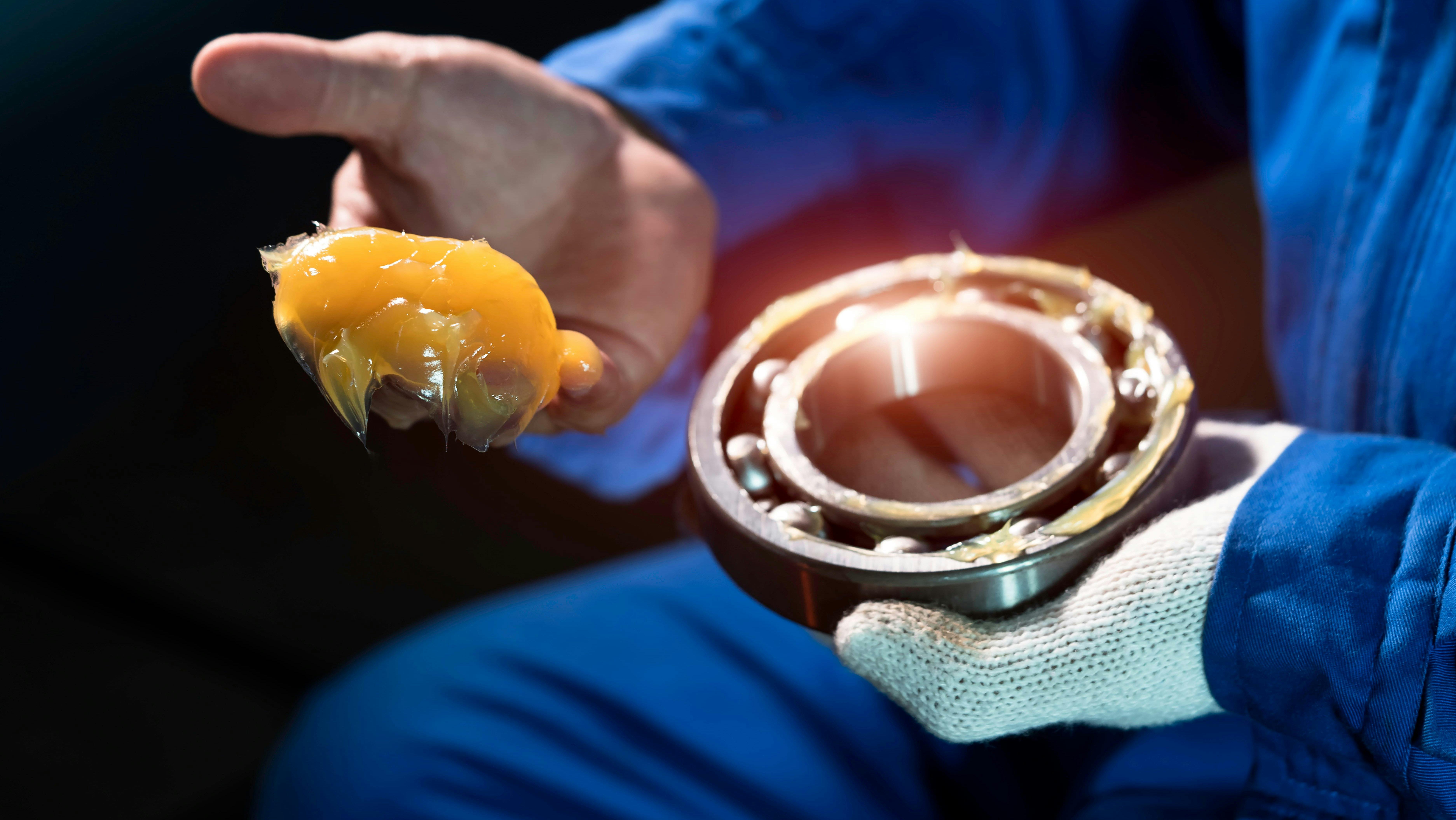 Chevron grease. Man with grease on his hand holding a component.