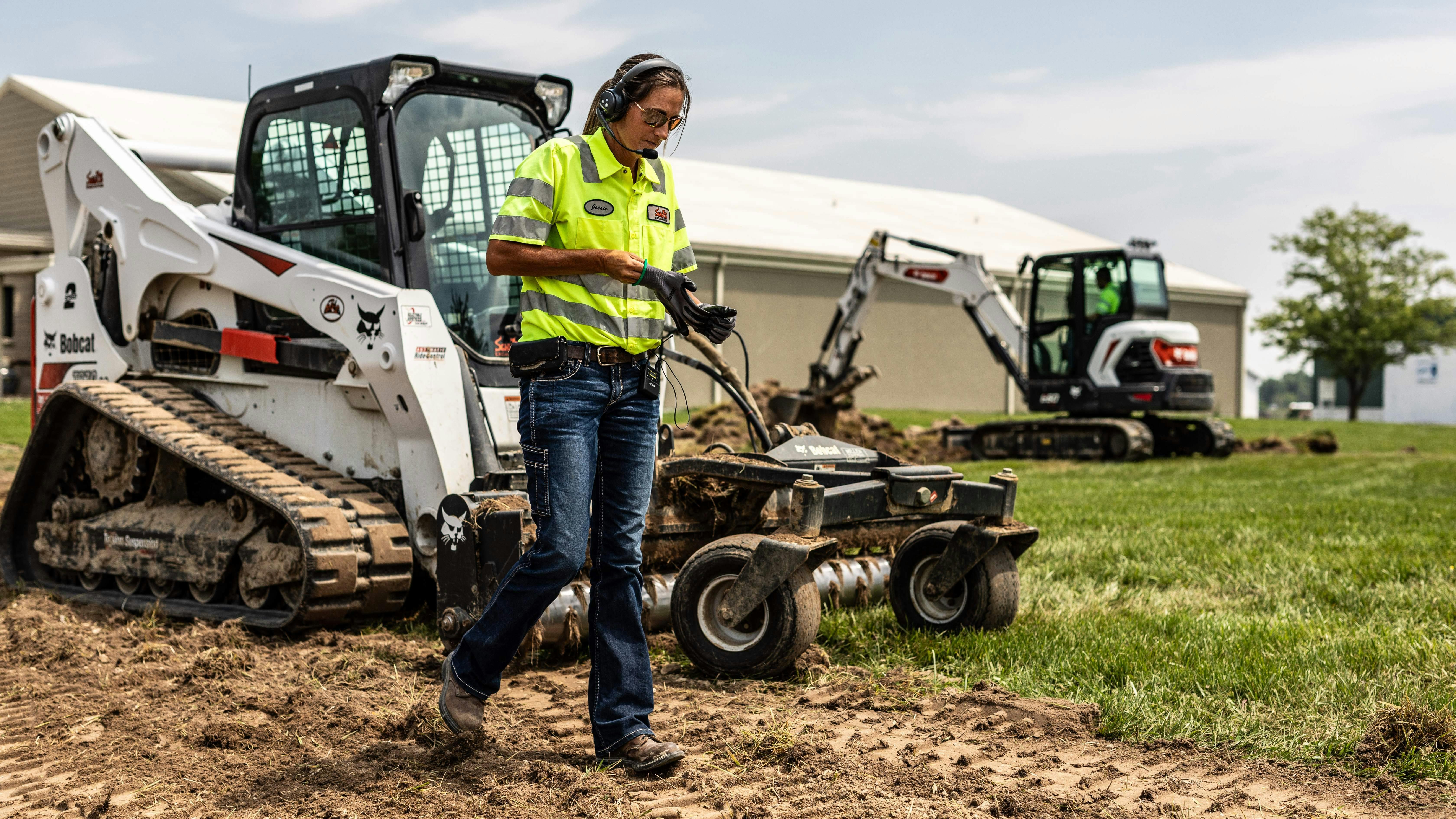 Worker walks along Bobcat compact track loader.