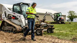 Worker walks along Bobcat compact track loader.