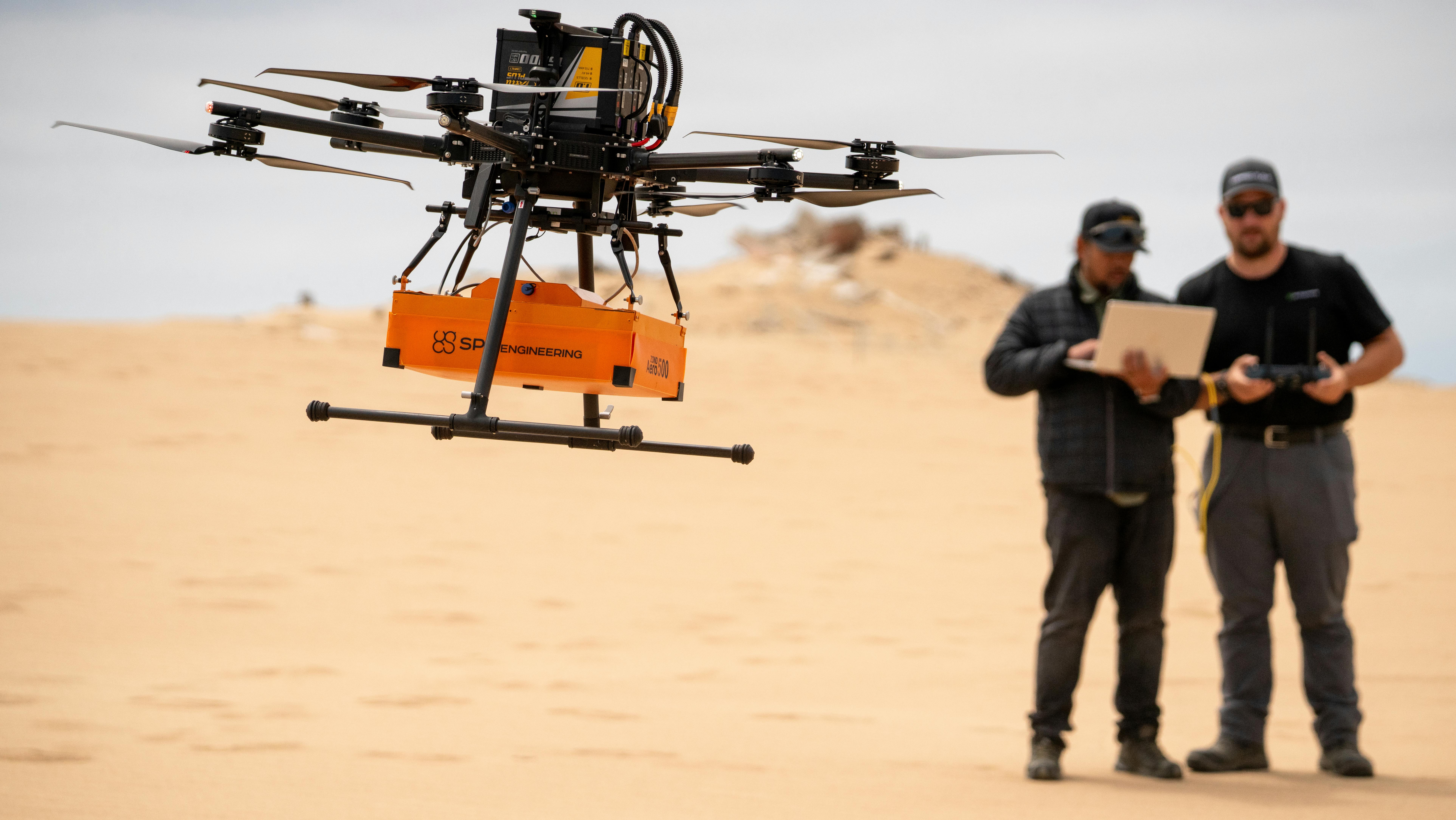 SPH Engineering drone services. Two men in the desert operate a drone with a sensor.