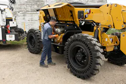 Cat TH0642 telehandler maintenance. Man inspects engine bay. Cat TH0642 telehandler maintenance. Man inspects engine bay.