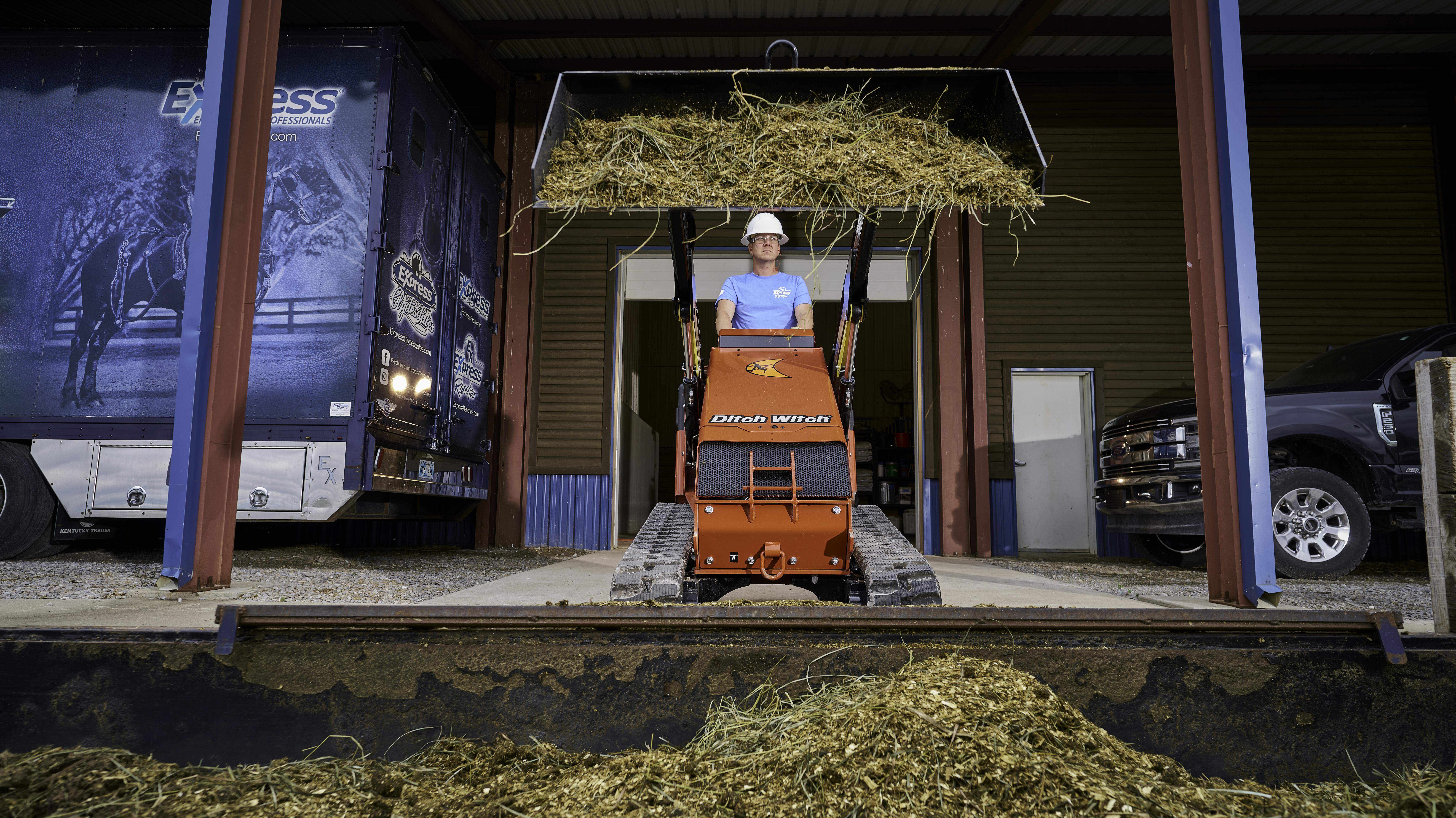 Ditch Witch SK1000 mini skid steer lifting hay on a loading dock.