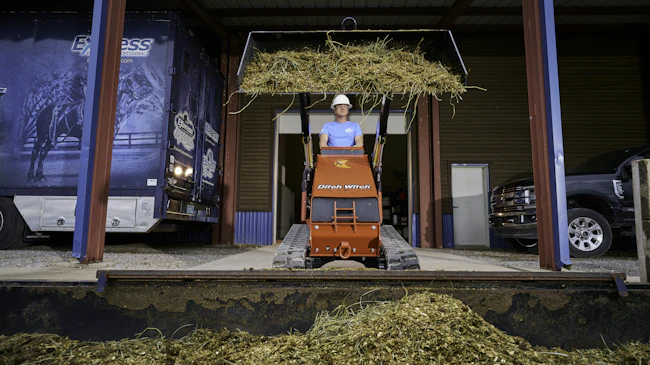 Ditch Witch SK1000 mini skid steer lifting hay on a loading dock.