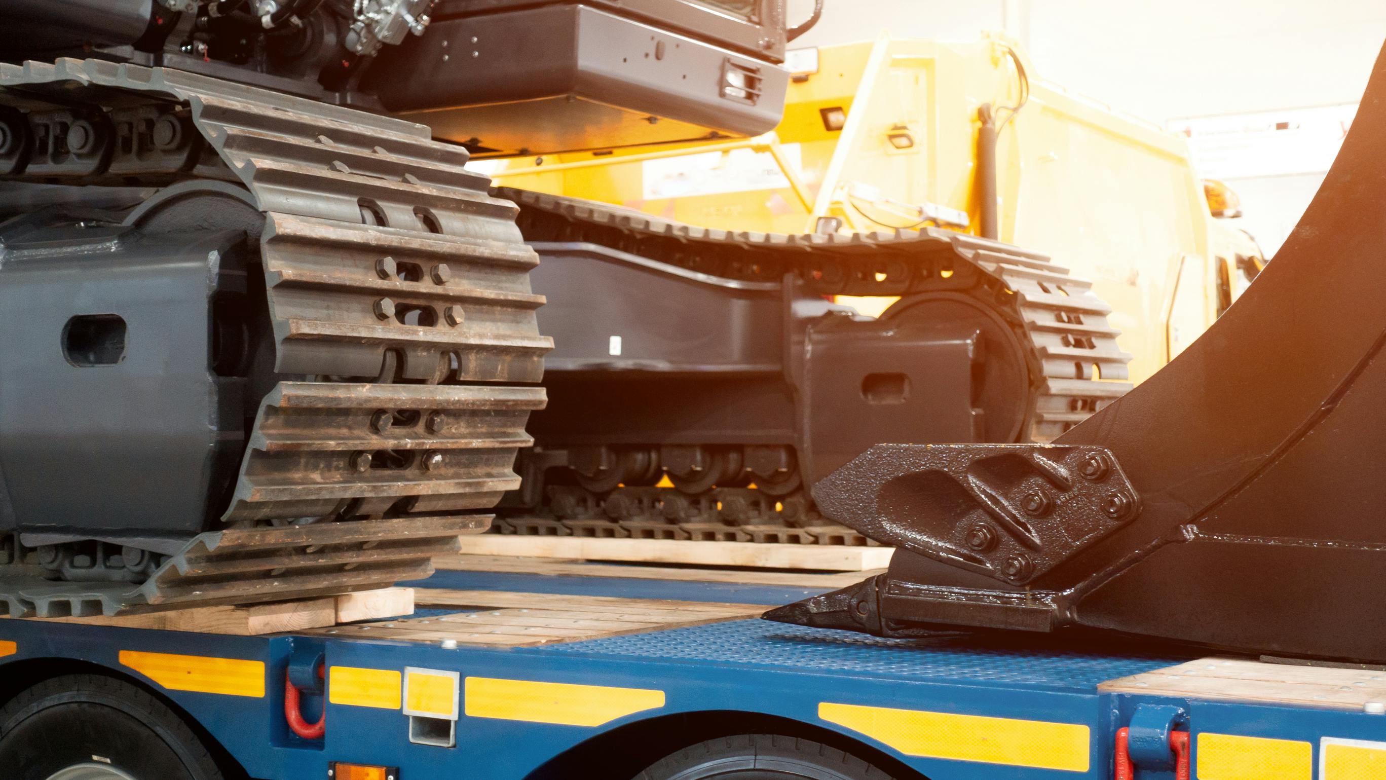 Excavator sitting on a trailer with sunlight streaming in.