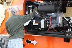 JLG telehandler maintenance. Man checks engine bay. JLG telehandler maintenance. Man checks engine bay.