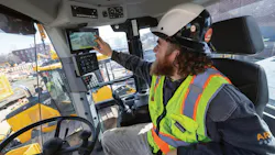 John Deere wheel loader equipped with AI camera system. Operator examines the camera monitor. John Deere wheel loader equipped with AI camera system. Operator examines the camera monitor.