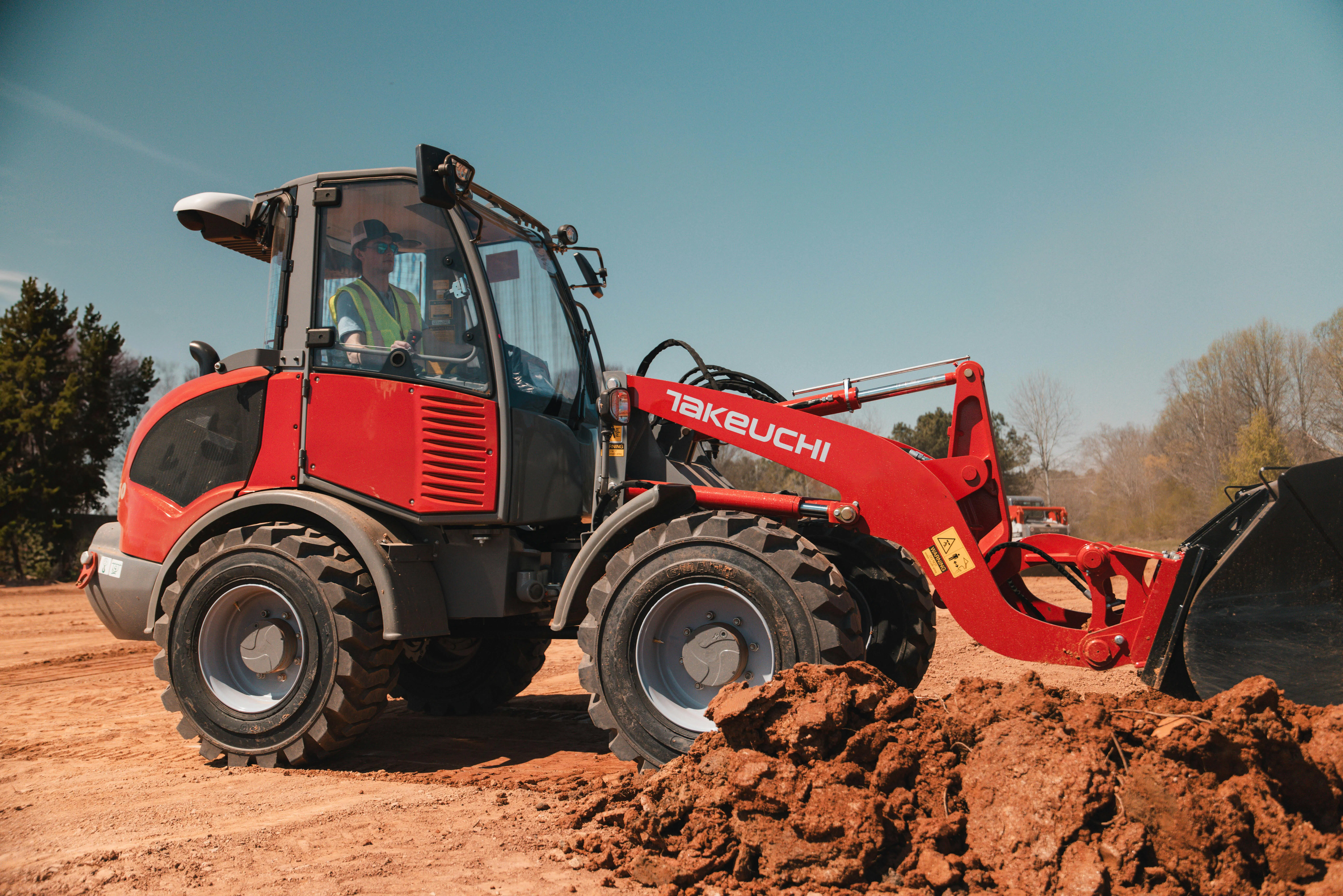 Takeuchi compact wheel loader digging some dirt.