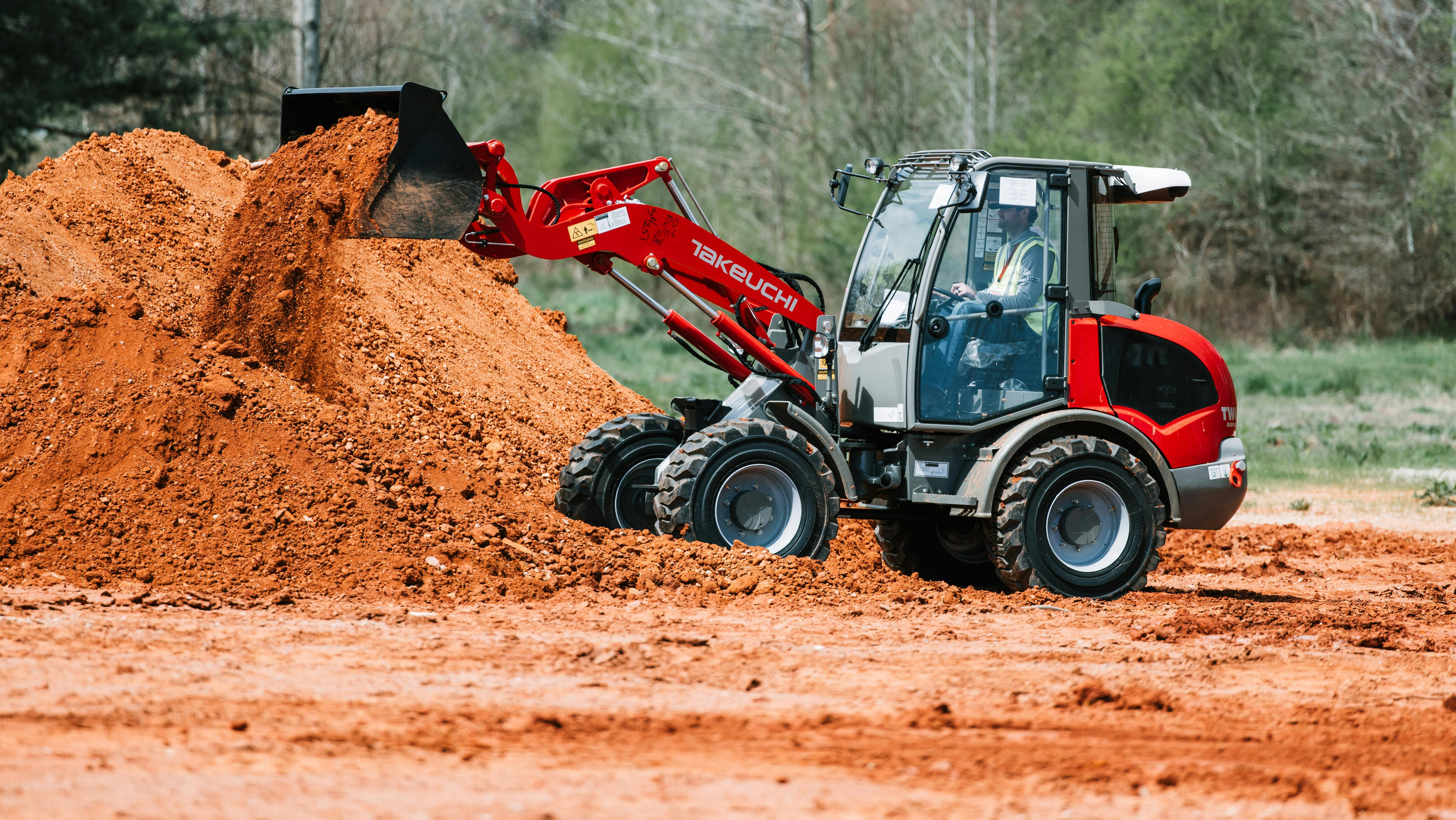 Takeuchi compact wheel loader dumping dirt into a pile.