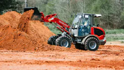 Takeuchi compact wheel loader dumping dirt into a pile.