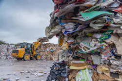 Caterpillar compact wheel loader lifting a pallet at a recycling center.