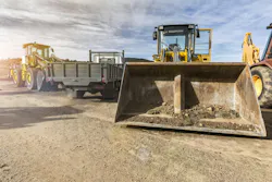 Heavy rental machinery for construction sitting in a dirt lot.