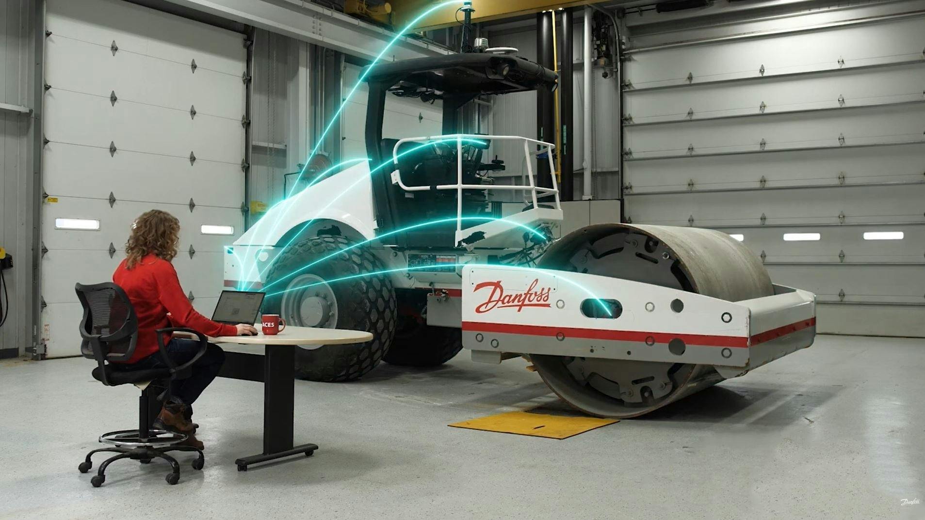 Aces roller with Danfoss logo. Woman on laptop shooting updates to roller.