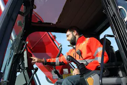 Operator touching a control panel on an excavator.