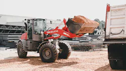 Takeuchi compact wheel loader carrying fresh dirt to a dump truck.