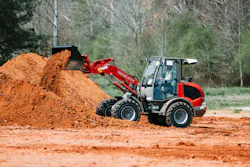 Takeuchi compact wheel loader dumping dirt into a pile.