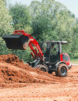 Takeuchi compact wheel loader dumping dirt into a pile.