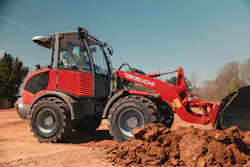 Takeuchi compact wheel loader pushing it's bucket through the dirt.
