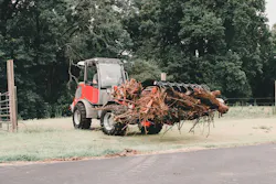 Takeuchi TW60 using a grapple attachment to carry brush debris.