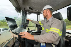 John Deere JDLink. Technician runs a computer in a wheel loader cab.