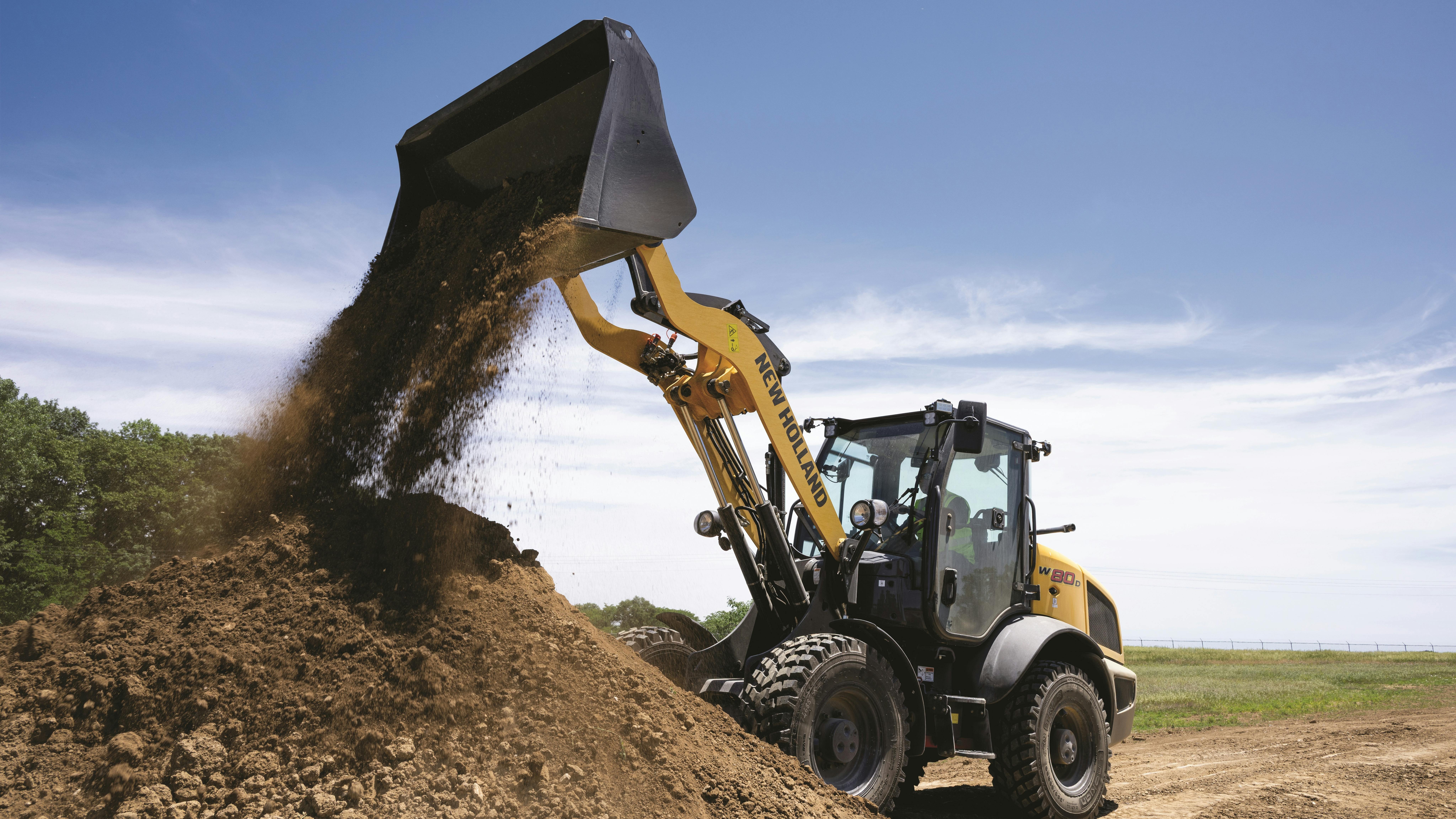 New Holland D-Series W80 compact wheel loader dumping dirt.