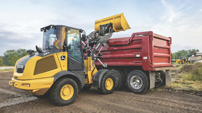 John Deere 244 compact wheel loader, dumping into a dump truck.