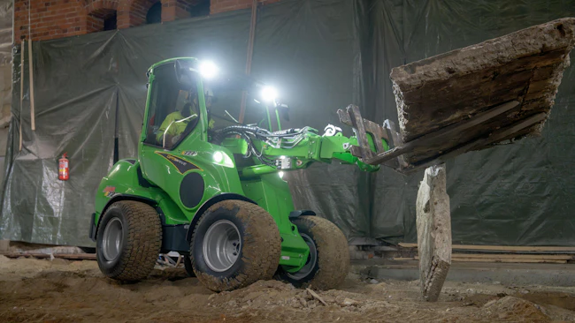 Avant Tecno USA e727 small articulated loader using pallet forks to move concrete.