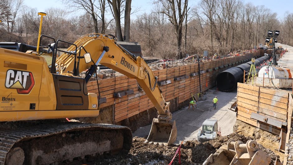 Excavator in trench with pipe